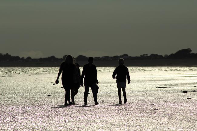 Sillouette of a group of people walking on west beach