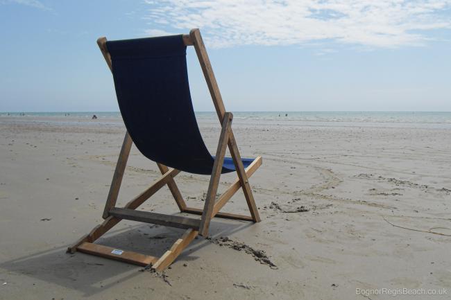 Single blue deckchair on the sand at Bognor Regis beach