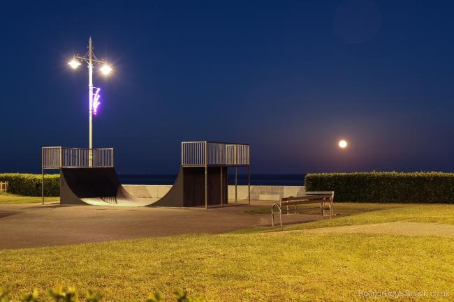 Nightime view of the skate park and lights by the promenade with rising moon